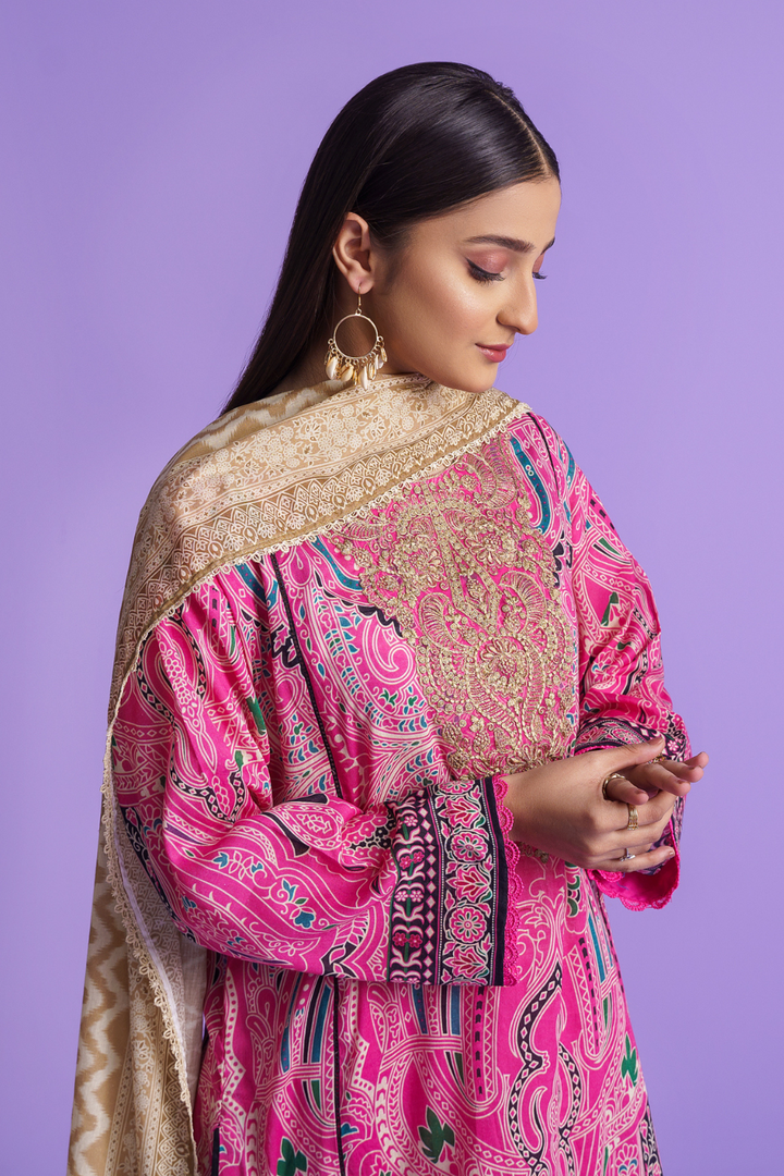 the side view of a woman wearing a pink and gold embroidered suit and she plays with her fingures.